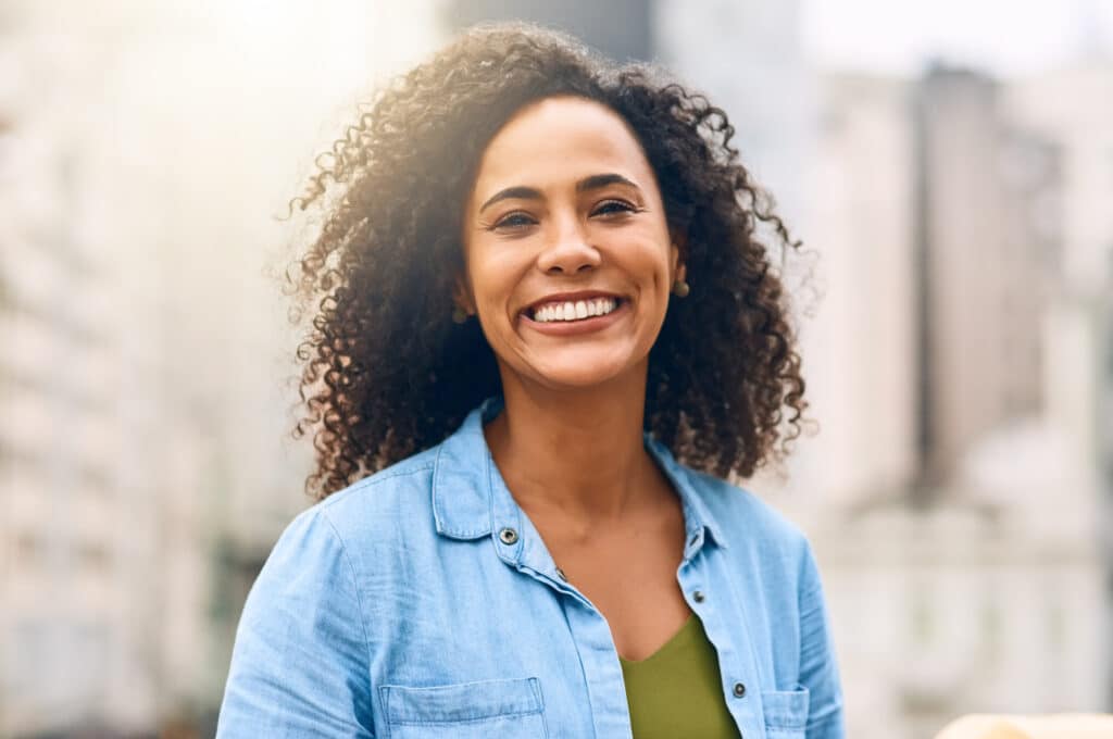 Smiling woman in blue shirt outdoors with urban background