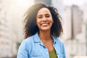 Smiling woman in blue shirt outdoors with urban background
