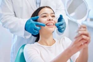 Dentist examining patient's teeth during dental checkup in professional office setting.